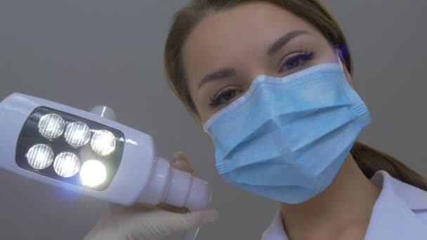 Meisje tandarts in masker houdt een tandheelkundige haak permanent op een arts patiënt is gekleed in Lab jas handen in handschoenen onderzoeken een tandheelkundige kliniek van tanden — Stockvideo