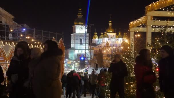 Lidé na osvětlené Sofiino náměstí Štědrý večer laserové paprsky temné obloze šťastní lidé zdobené jedle stromy Sophia Cathedral nový rok večer — Stock video