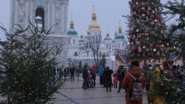 Pareja joven en la plaza decorada Sophia Animador de abeto decorado de Navidad en traje de oso Campanario de una catedral Firs decorado con lámparas Kiev — Vídeos de Stock