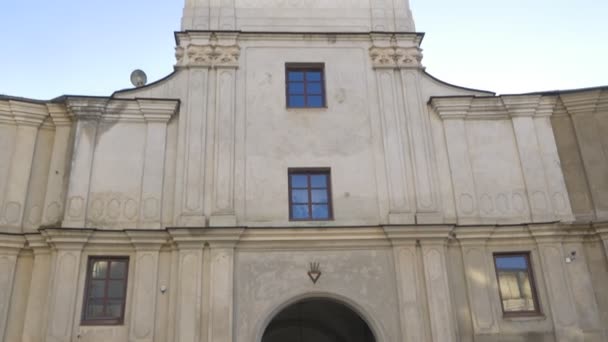 Mensen wandelen door boog Karmelieten klooster in Berdichev beschermende muren torens in een oud gebouw in barok stijl katholieke Vintage zonnige Oekraïne — Stockvideo