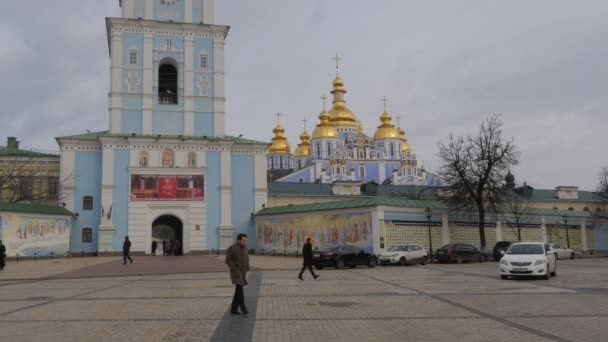 Persone al Monastero con cupola d'oro di Tower Michael a Kiev Ucraina Orologio della Chiesa su una torre Angeli d'ingresso ad arco Dipinti ad affreschi Giorno nuvoloso — Video Stock