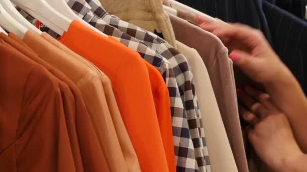 Женщина берет оранжевое платье глядя на одежду, выбирая одежду Женская одежда Магазин Брюнетка Женщина покупает одежду бутик одежды на тремпели — стоковое видео
