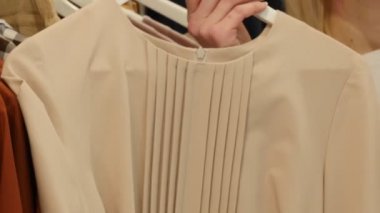 Woman Takes a Beige Dress Tries Talking by Phone Choosing a Clothes Womenswear Shop Client Blonde Woman Buying a Clothes Boutique Dresses on Trempels