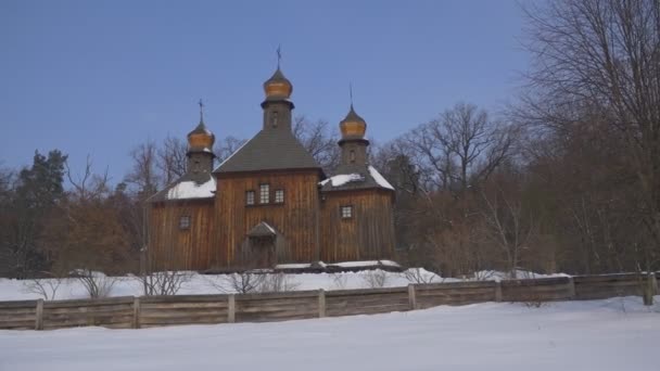 Três torturou a velha igreja de madeira Neve em uma Igreja de Inverno Terreno do Santo Michael o Arcanjo Pirogovo Casas rústicas Árvores Brancas nuas Ucrânia — Vídeo de Stock
