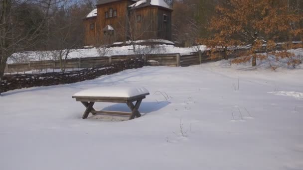 Alter hölzerner Kirchentisch bedeckt mit Schnee rustikales Haus Winter trockene Blätter auf einem Eichenbaum Weidenzaun Kirche heiliger Michael der Erzengel pirogovo Ukraine — Stockvideo