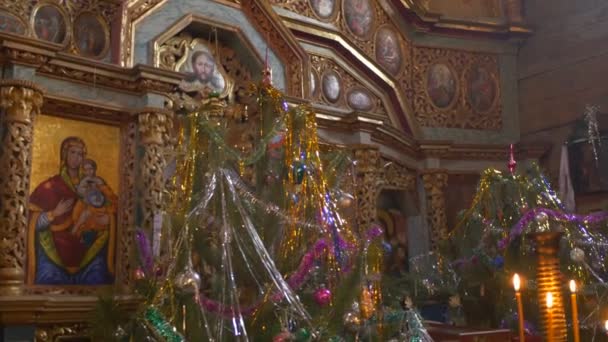 Panorama Iglesia de Paraskeva Pirogovo Navidad Iconos interiores con toallas bordadas Imágenes en marcos dorados Velas ardientes Árbol de Año Nuevo Ucrania — Vídeo de stock