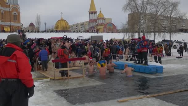 Celebrazione del Battesimo Ortodosso Le persone stanno facendo il bagno nel buco a forma di croce Battesimo di Kiev di Gesù Cristo Embankment of Dnieper Near to Cathedral of Intercession — Video Stock