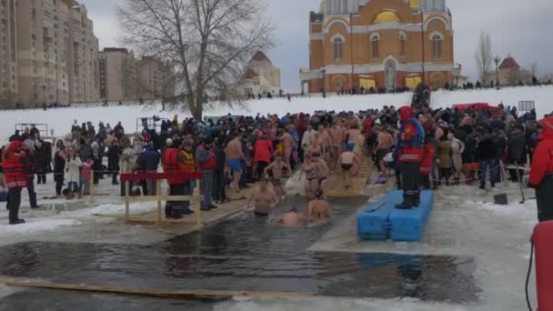 Celebrazione del Battesimo Ortodosso a Kiev Persone che fanno il bagno nei fori incrociati Battesimo di Gesù Cristo Dnieper Vicino alla Cattedrale del paesaggio urbano di intercessione — Video Stock