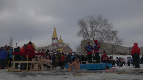 キエフの人々の正統なバプテスマのお祝いは、休憩の大聖堂の近くにイエス・キリスト・ドニエパーのバプテスマを実行する冷たい水に浸る人々 — ストック動画
