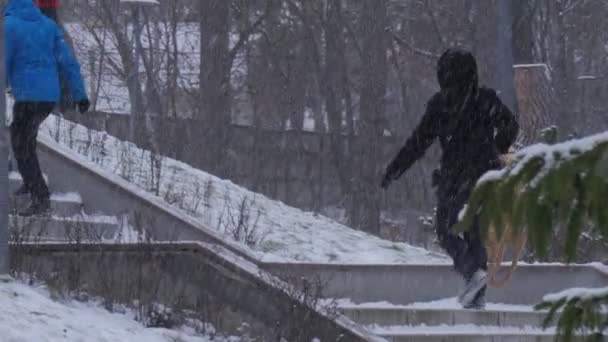 Donna sta portando una slitta Arrampicata sulle scale Bambini in sella a una slitta giù dalla montagna Inverno Bambini e genitori Trascorrere del tempo Parco in Bucha Ucraina — Video Stock