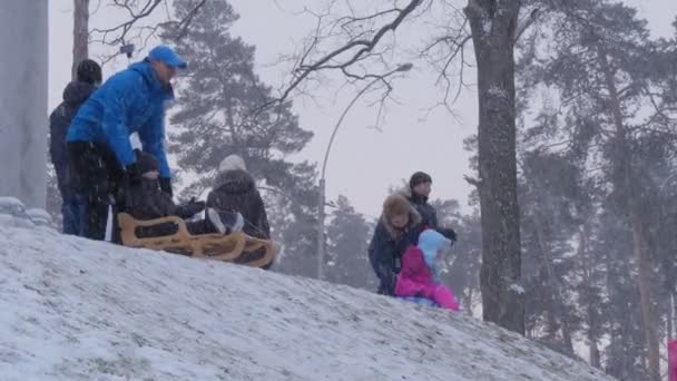 Pais Empurra um Sleighs Bucha Ucrânia Crianças Montando em um Sleigh Downhill Inverno Crianças e Pais Passando o tempo juntos Divirta-se Parque em Bucha Ucrânia — Vídeo de Stock