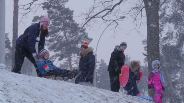 Рождество в Буча Украина Родители толкают детей на санях катание на санках Зимние родители находятся на холме Семьи проводят время вместе — стоковое видео