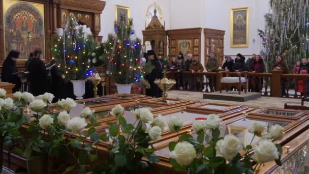 Pueblo y Clero Navidad Montaña Santa Lavra Dormition Catedral Ucrania Hombres con vestiduras negras están cantando La gente está escuchando Firs decorados Vela — Vídeos de Stock