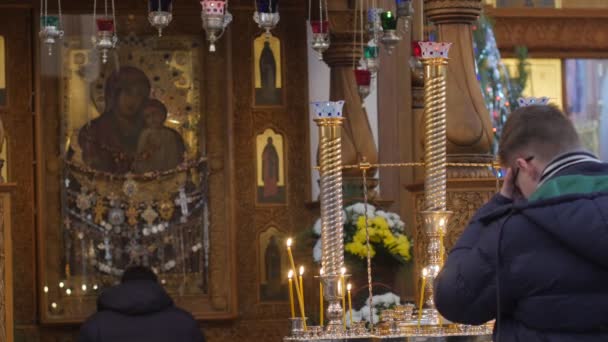 Homme priant à l'image Dormition Cathédrale Adorateur de Noël en face de l'icône Bougies brûlantes Sainte montagne Lavra Ukraine décoré sapins d'or Décor — Video