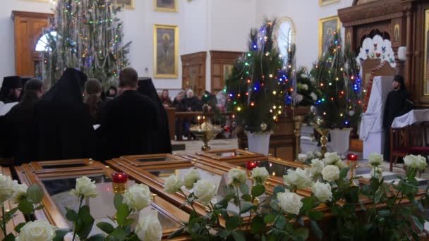 Gruppe von Geistlichen Weihnachten heiliger Berg Lavra Entschlafungskathedrale ukrainische Männer in schwarzen Gewändern singen Menschen hören Neujahrsbäume Blumen — Stockvideo