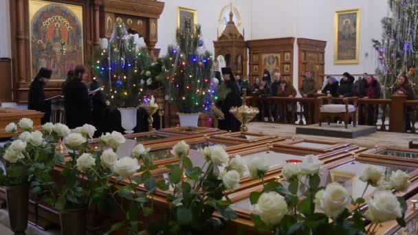 Pueblo y clero Navidad Montaña Santa Lavra Dormition Catedral Ucrania Hombres con vestiduras negras están cantando La gente está escuchando Lámpara de árboles de Año Nuevo — Vídeo de stock