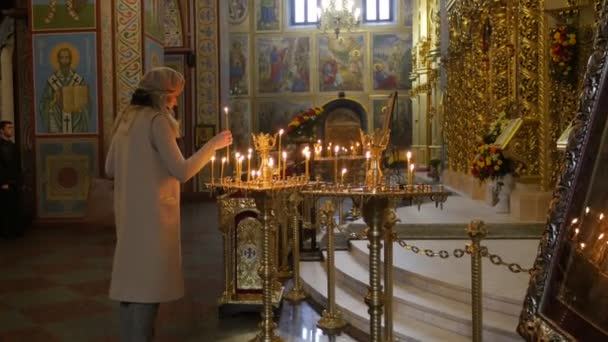 Mulher no Mosteiro Masculino de São Miguel Véspera de Natal Mulher de Kiev Queima uma Vela Beija a Imagem Orando em um Salão Negro da Igreja Imagens Ícones Velas — Vídeo de Stock