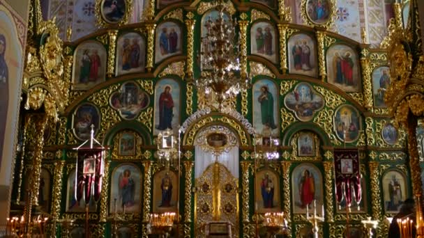 Iconostasis gustinetskiy weibliches Kloster ukraine Heiligabend Kerzen brennen religiöse Bilder in goldenen Rahmen Kruzifixe Panorama einer Wand — Stockvideo