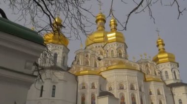Bir ağacın arkasında parlayan kilise Cupolas beyaz duvarlar ve altın Cupolas Dormition Katedrali kutsal Dormition Kiev-Pechersk Lavra Ukrayna kış gündüz