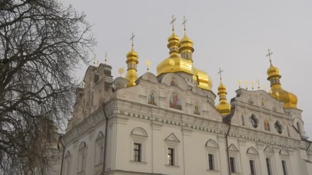 Panorama över kyrkliga vita väggar gyllene kupoler heliga Dormition Kiev-Pechersk Lavra Dormition domkyrkan exteriör av en ortodox kyrka kala grenar träd — Stockvideo