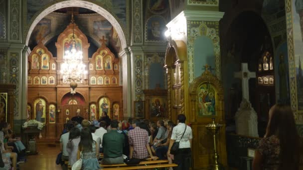 Jsou lidé v Nejsvětější Trojice Jonáš klášter Kyjev Ukrajina Nanebevzetí Marie interiéru pravoslavné církve lidí sedí na lavičky a poslech — Stock video