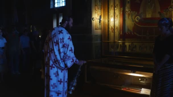 Prästerskapet vid Service Trinity kloster firande av Mary Dormition Kiev prästerskapet vajande med en brännare potten tillbedjare står runt i en mörk Hall — Stockvideo