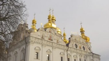 Dış Dormition Katedrali Golden Cupolas beyaz duvarlar dekoratif çit sokak lambaları kilise bölümü, Kiev-Pechersk Lavra Panorama Ukrayna bulutlu günüdür
