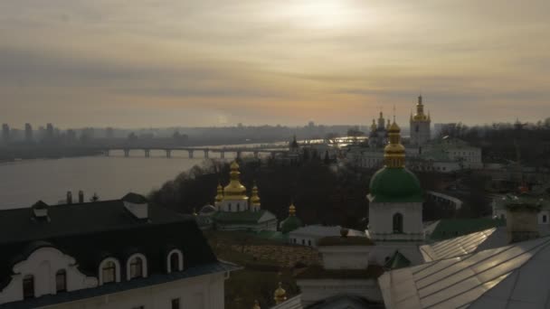 Sol brilla Kiev-Pechersk Lavra Panoprama Ucrania Sol a través de las nubes Dnepr Paton puente a través del río Kiev ciudad en un horizonte puesta del sol cielo nublado — Vídeo de stock