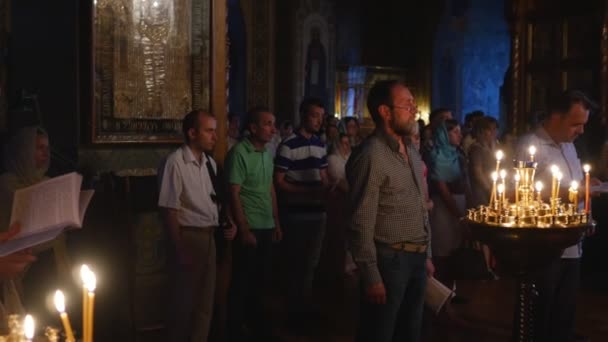 Οι άνθρωποι του Ιωνά υπηρεσία Τριάδος Μονή εορτασμούς για Κίεβο Κοιμήσεως Θεοτόκου γυναίκα με το κεφάλι καλυμμένο κρατώντας ένα βιβλίο κεριά είναι καύση σκοτεινή αίθουσα — Αρχείο Βίντεο