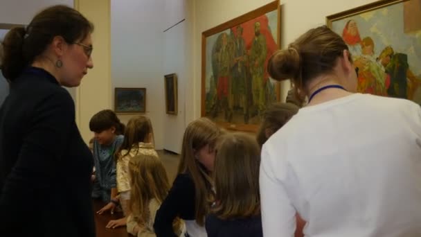 Enseignant Enfants Excursion au Musée national d'art à Kiev Veille de Noël Ukraine Enseignant en lunettes montre les peintures sur papier Enfants écoutent sourire — Video