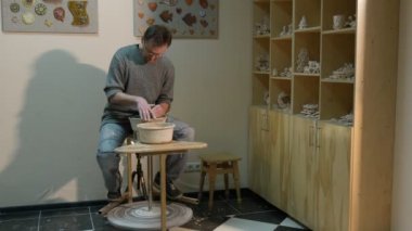 Potter bir kil kavanoz döndürerek bir çanak çömlek çarkı hevesle çalışma konusunda bir tekerlek kalıplama veya seramik zanaat çanak çömlek Atölyesi Pot orta yaşlı öğrenci öğrenme