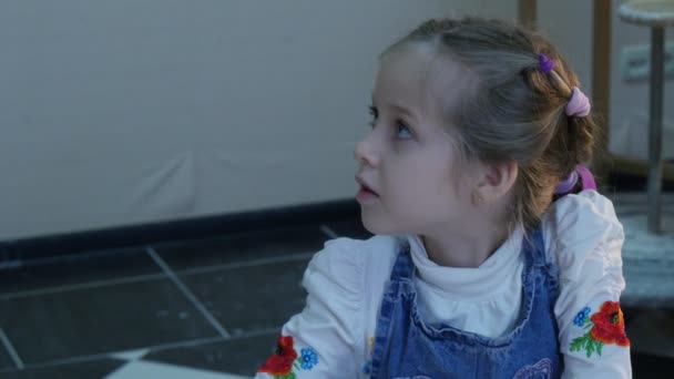 Kid est de découper une figurine en argile enseignant aide la fille avec spatule couteau Kid essaie de se couper brosses sont sur une table désordonnée Kid atelier de poterie — Video