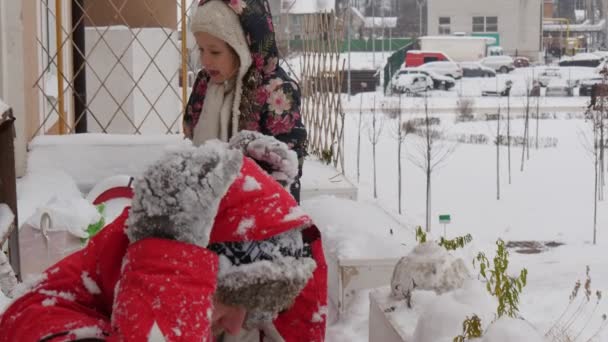 Muž Kid buduje sněžný plastik hrající sněhové koule u okna v rodině v Cornice se směje s otcem a jeho dcerou — Stock video