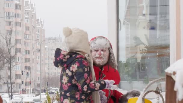 Kid en vader speelt sneeuwballen op balkon sneeuw op de gezicht familie van de vader speelt in de buurt van het raam op een cornice de tijd samen doorbrengen — Stockvideo