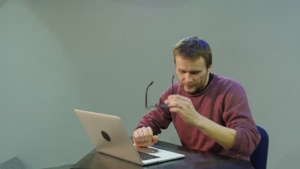 남자는 빠른 미소를 입력 하는 노트북 을 닫습니다 그의 팔에 기대어 생각 하는 노트북 프리랜서 프로그래머 카피 라이터 디자이너 회계사 열심히 일 하 고 열립니다. — 비디오