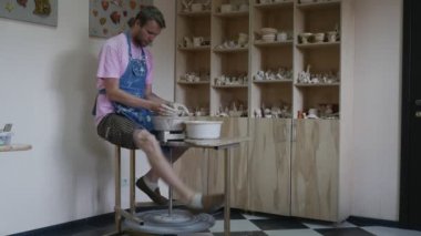 Dostum Potter bir Pot çalışmaya çömlek tekerlek öğrenme bir çanak çömlek zanaat çanak çömlek Atölyesi adam kot önlük dönen bir tekerlek bacak tarafından yapım bir tekerleği dönen