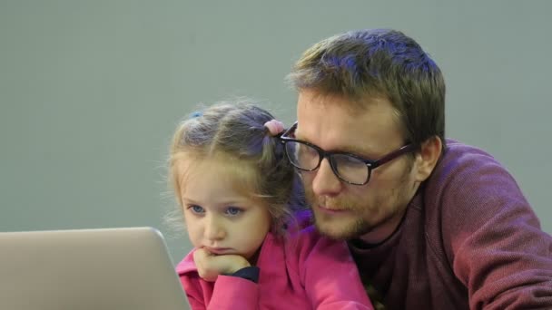 Kind en vader zijn het verkennen van het Internet-papa praten klikken een Laptop zijn dochter leert te werken met de Laptop Man en kind zitten aan de tafel — Stockvideo