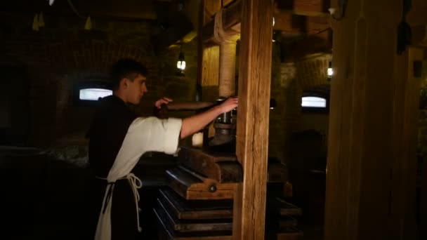 Junger Mann kreist eine Presse Papierherstellungstechnologie arbeiten mit uralten Handwerksmuseum in Radomyschl Kerl in Tracht alten Werkzeugen dunklen Raum — Stockvideo