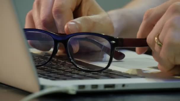 Männerhände, die mit Laptop arbeiten, halten eine Brille im Gespräch Mann denkt eine Weile nach Freiberufler Programmierer Werbetexter Designer Buchhalter arbeitet hart — Stockvideo