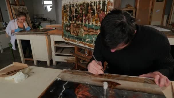 Žena muže umělců na jejich ikony obnovení pravoslavné obrazy opravy Shop Panorama obnovení skupiny pracovních pracuje ve studiu malby na stojany — Stock video