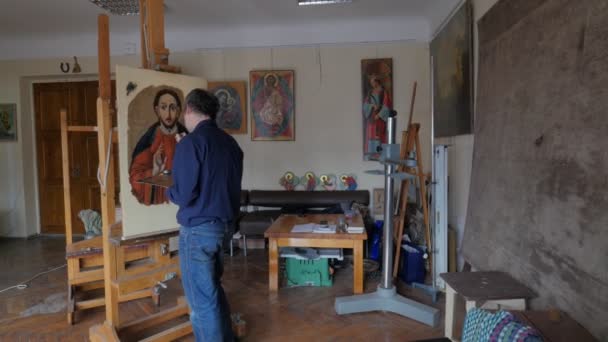 Kunstenaar herstellen pictogram van orthodoxe Saint reparatie restauratie van de pictogrammen reparatie winkel restauratie groep werkt in de Studio Kiev schilderijen op een Schildersezels — Stockvideo