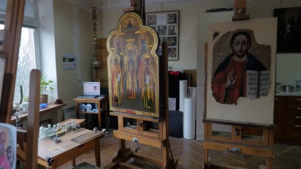 Man in glazen Vergrootglas herstellen pictogram orthodoxe iconen reparatie winkel restauratie groep werkt in de Studio in Kiev schilderijen op een schildersezels borstels — Stockvideo
