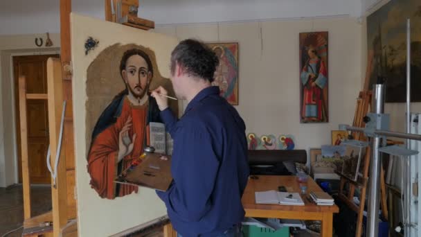 Artista Restauración de iconos ortodoxos Sosteniendo una paleta Reparación Restauración de los iconos Grupo de restauración está trabajando en el estudio Kiev Fotos en una pared — Vídeo de stock