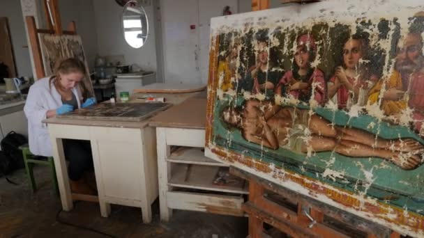 Nő művész visszaállítása sérült ortodox ikonok Repair Shop helyreállítása csoport dolgozik a stúdióban, Kiev régi kép egy festőállvány művész kesztyű — Stock videók
