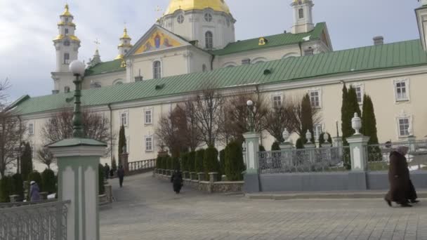 Ludzie są o Święty Dormition Poczajowskiej Lavra Zgromadzenia mężczyźni kobiety idą przez Alley aparat podejścia klasztor prawosławny na Ukrainie Poczajowskiej — Wideo stockowe