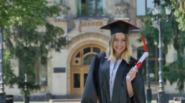 Woman in Mantle Raises Her Hands Shows Diploma Smiling Happy Graduand Standing in Alley Outside the Univesrsity Shakes the Diploma Sunny Summer Day