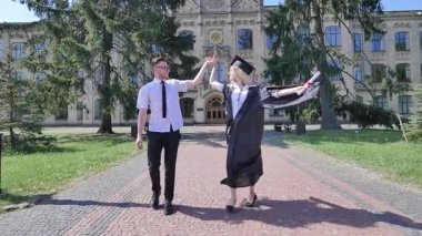Mutlu Graduands Holding Hands Woman Gömlek Manto Lu Ve Tie Güneşli Bir Günde Üniversite Çift Dışında Alley Yürüyüş Gülümseyen Kadın Twisting olduğunu