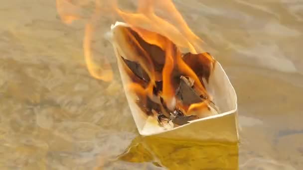 Papierschiff in Flammen auf der Wasseroberfläche Träume nicht wahr geworden verlorene Hoffnung Tod Katastrophe Papierschiff auf einem Flussmeer in sonnigem Tag sandigen Boden — Stockvideo