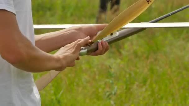 Mãos de menino segurando o modelo de aeronave na competição ao ar livre no campo verde Preparação ensolarada para modelos de lançamento de aviões Montagem Estimativa do voo — Vídeo de Stock