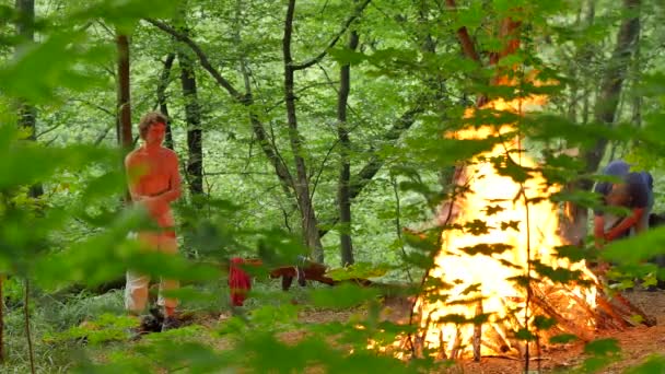 Gente viendo un incendio quemar Ivan Kupala de pie alrededor en el Festival Pagano Kiev Ritual de fogata Kindling auténtica celebración en el bosque árboles verdes anochecer — Vídeo de stock